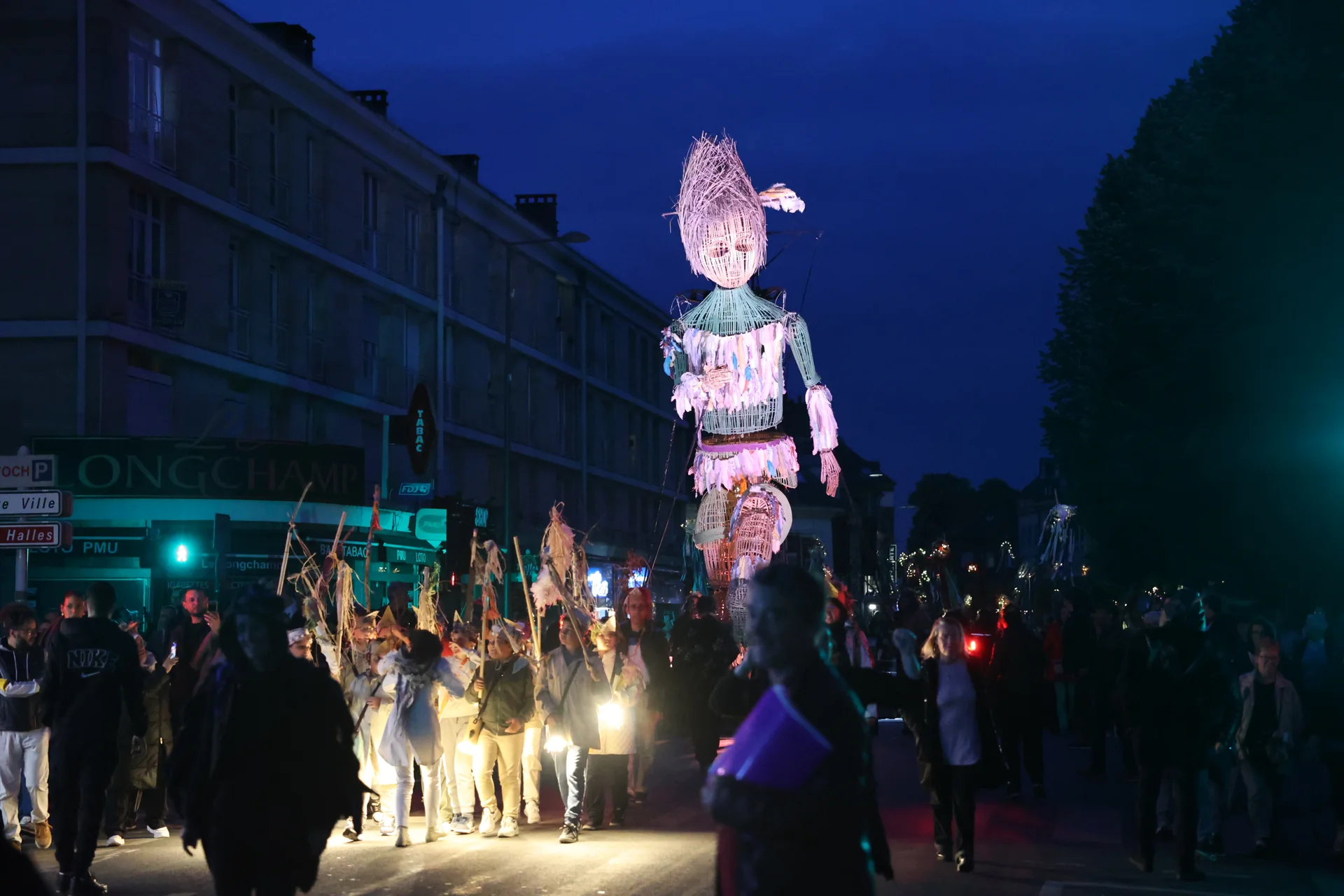 Plume et le cortège de La Cabane à Plume(s) dans une rue de Beauvais à la nuit tombée.