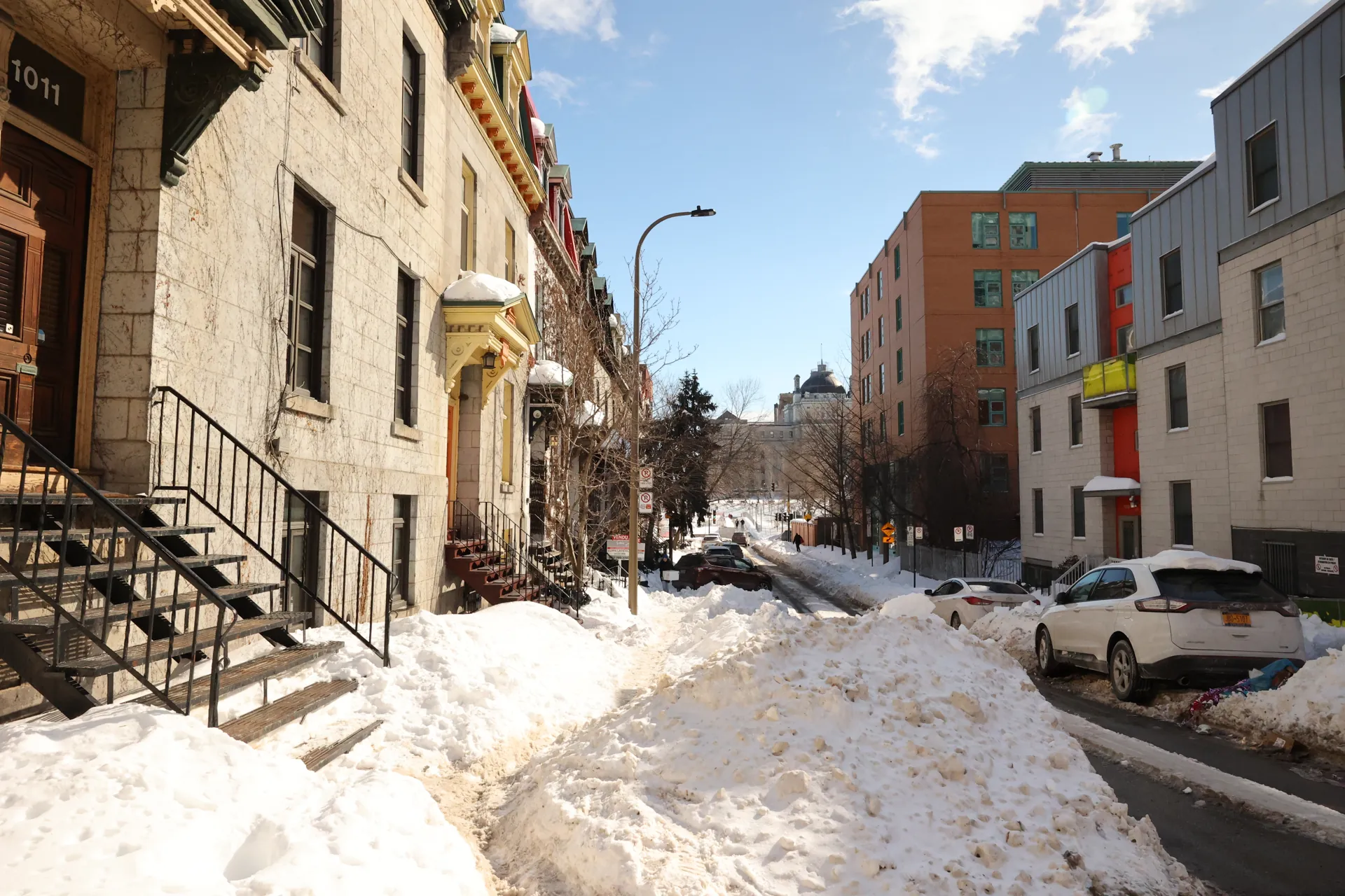 Rue montréalaise bordée de bâtiments et de larges amas de neige