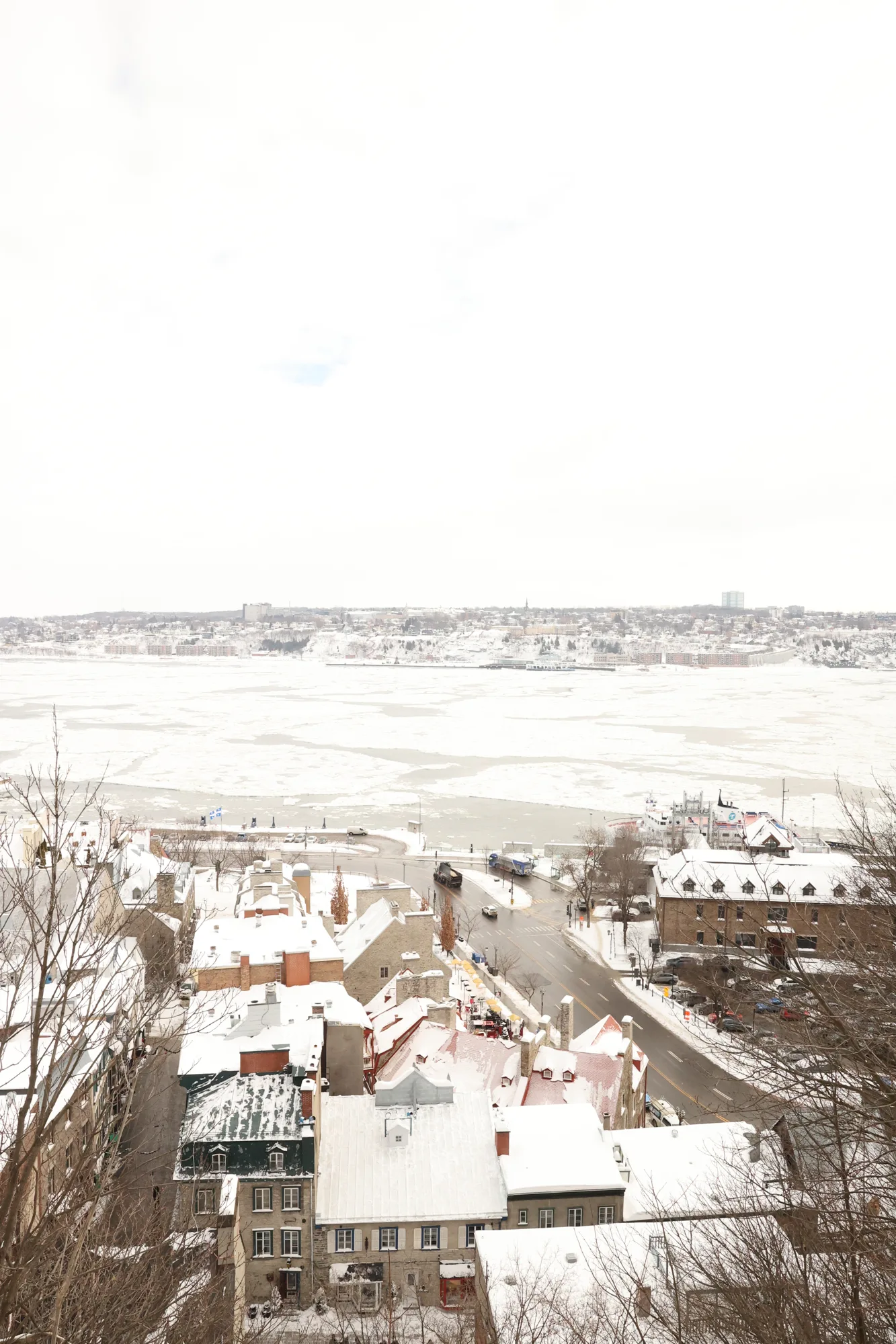 Depuis les hauteurs, les toitures enneigées conduisent le regard vers le Saint-Laurent.