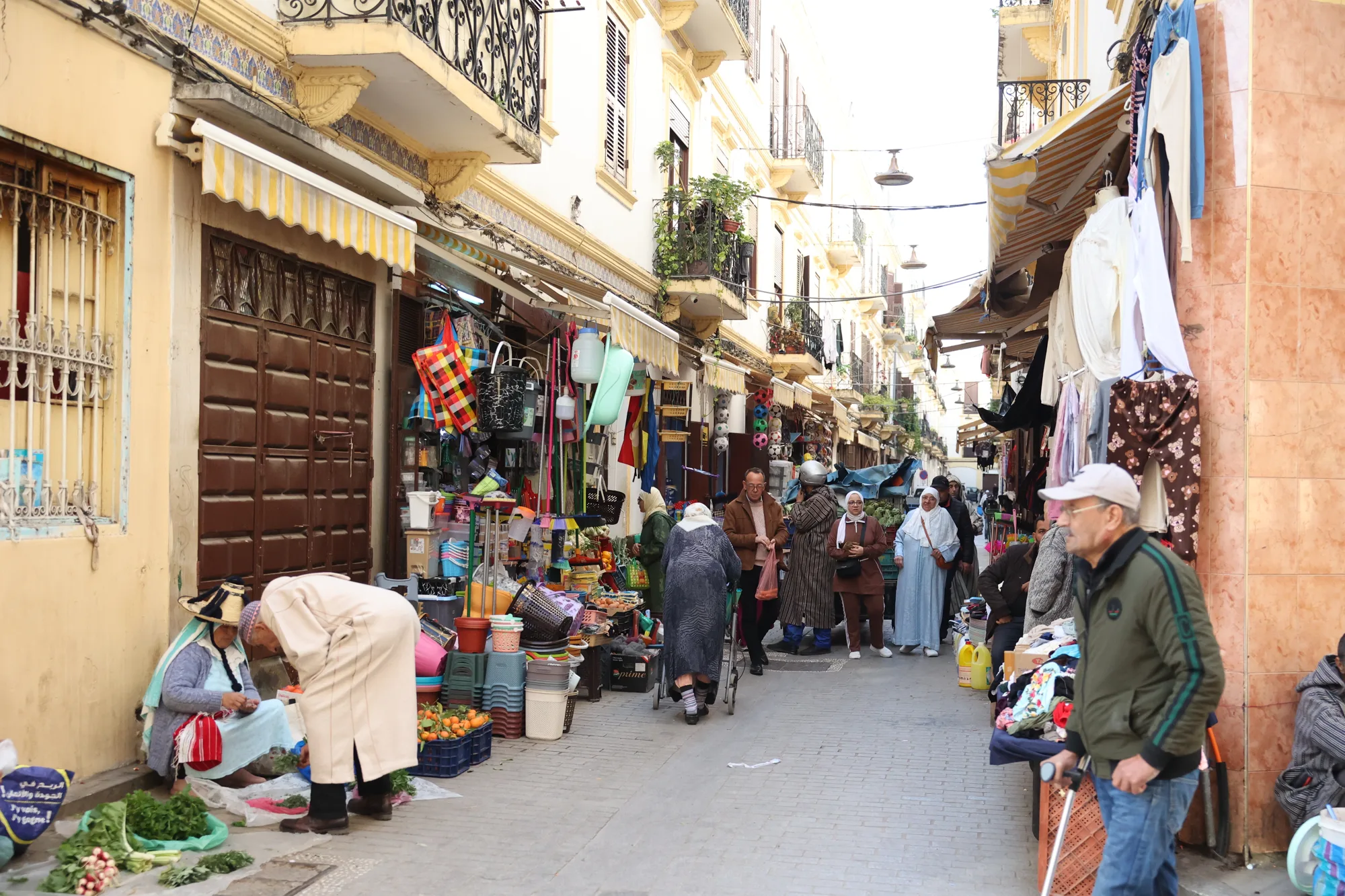 Une rue commerçante de la médina : les objets et les enseignes accompagnent le passage.