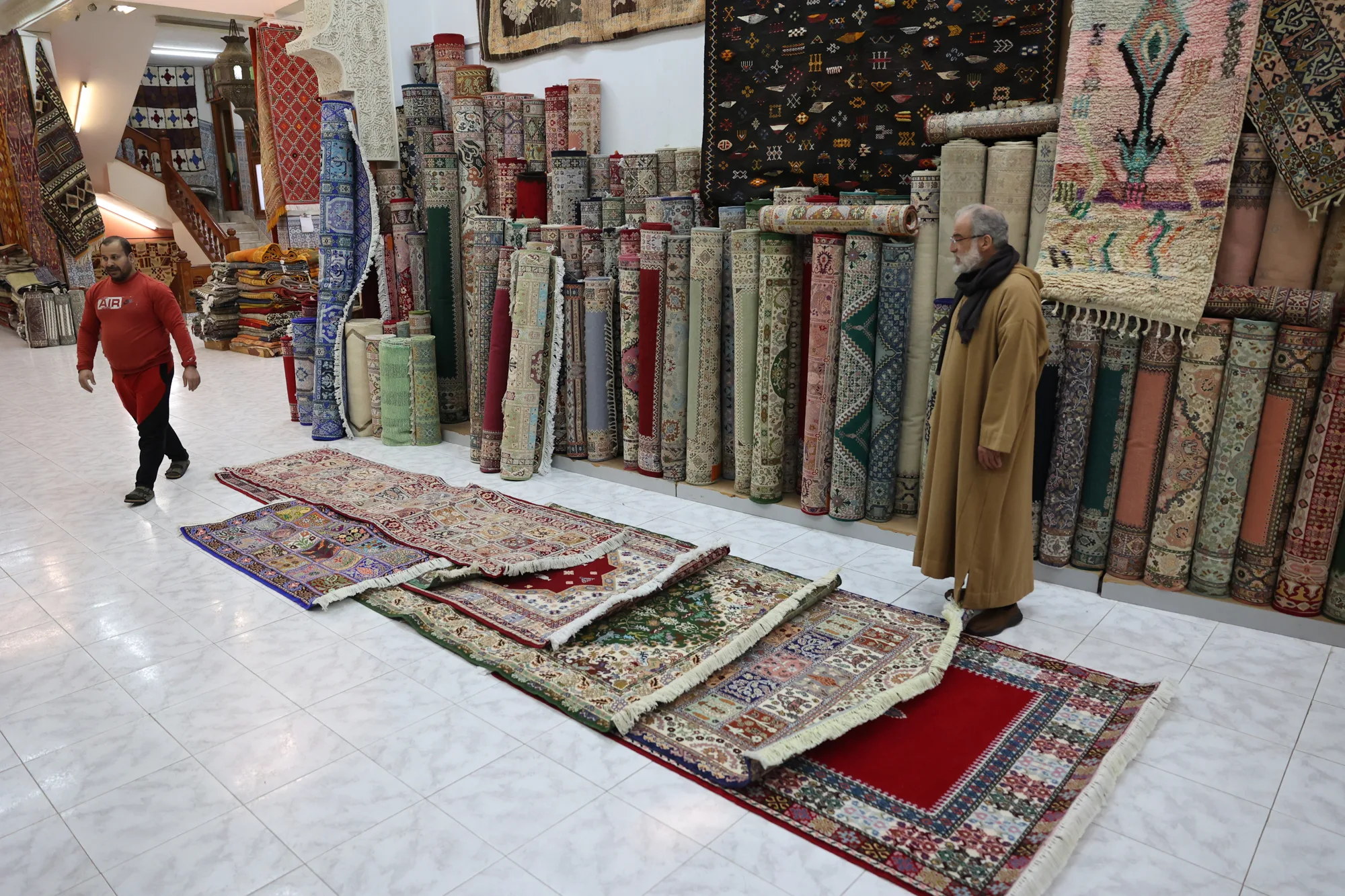Tapis déployés au sol et tissus alignés devant une boutique de la médina.