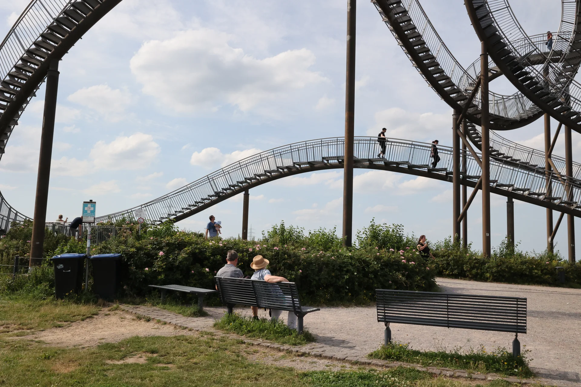 Des visiteurs assis sur un banc sous les passerelles de Tiger and Turtle.
